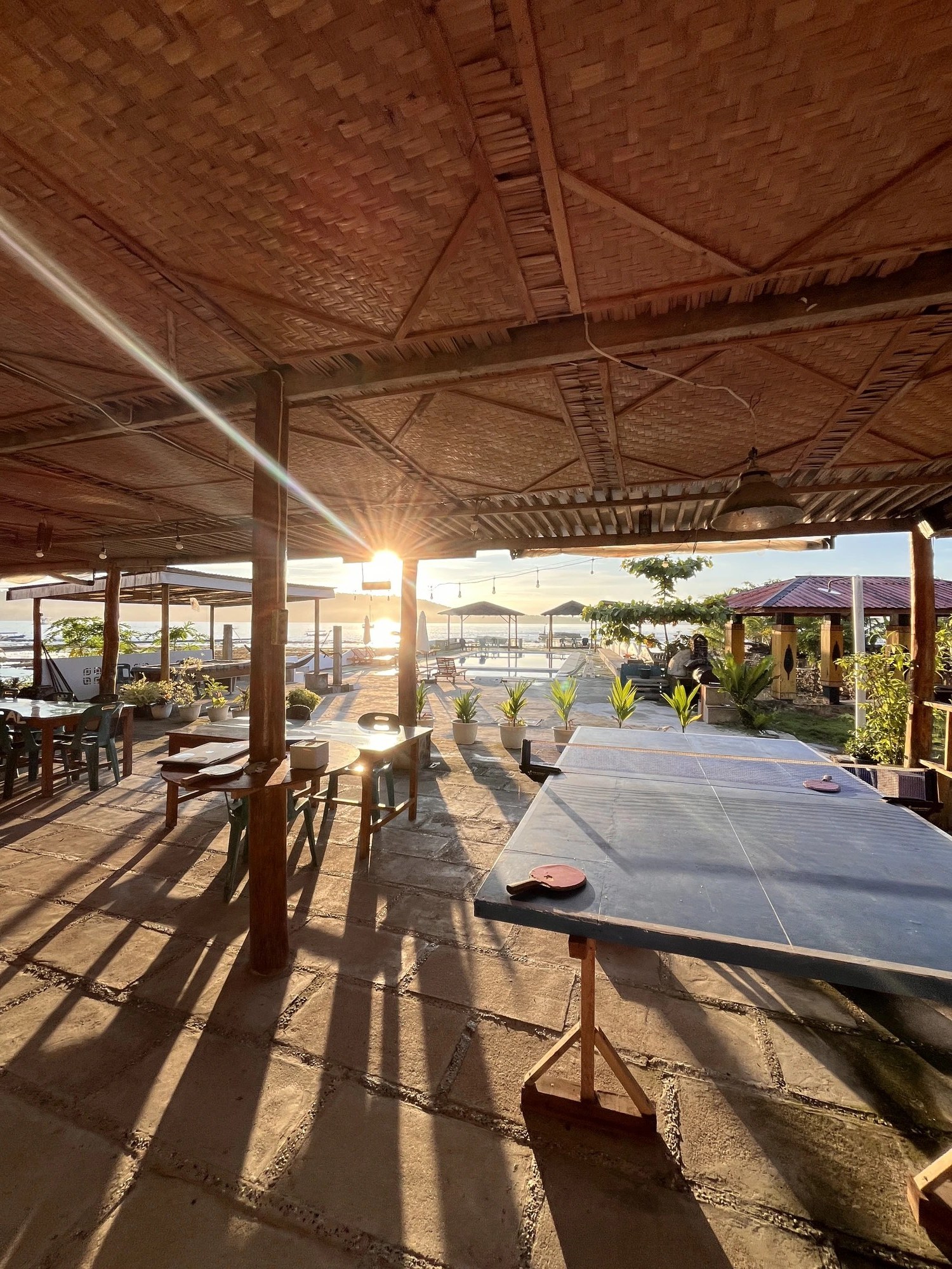 Pool deck and beachside restaurant at Raffiel Nias overlooking the ocean at sunset